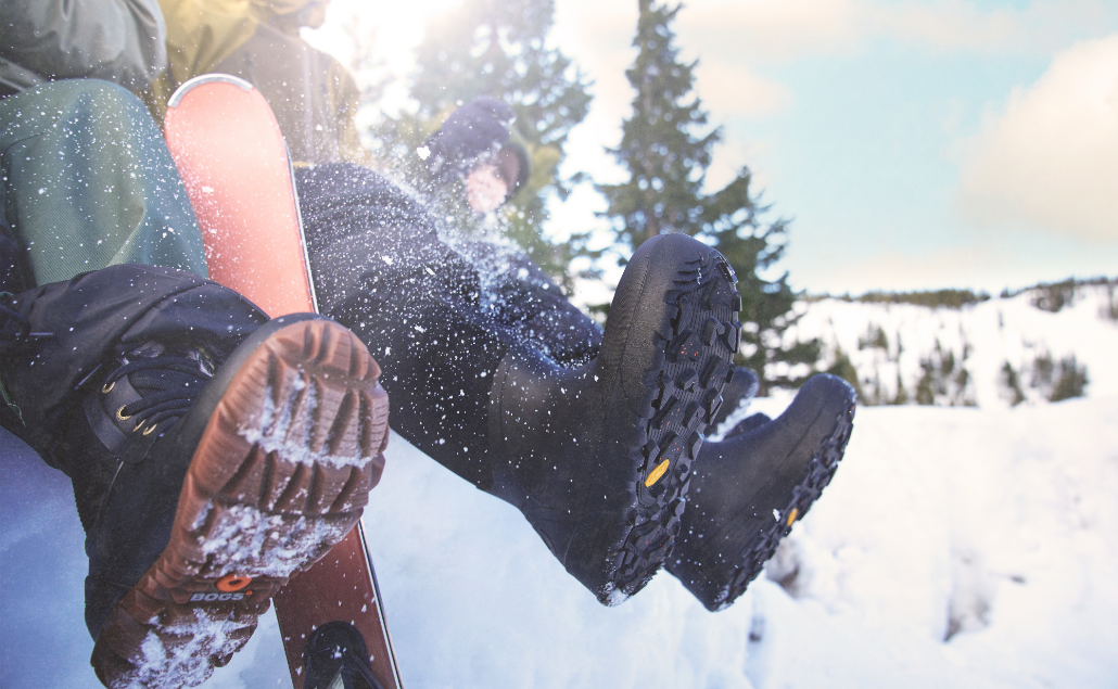 Image features the bottom of various Bogs boots in the snow. 